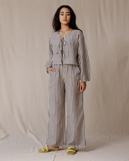 - What it is: A matching linen two-piece set consisting of a striped long-sleeve button-front top with a tie detail and wide-leg pants.
- Intended audience: Women (model styling and fit suggest female sizing and cuts).
- Notable attributes: Black and white vertical stripes, lightweight linen fabric, loose relaxed silhouette, tie-front top, elastic or wide-leg pant, and flat sandals shown for styling.