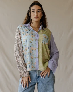 - What the product is: A long-sleeve, button-down shirt featuring a patchwork collage of different patterned and colored panels.
- Intended audience: Women (model styling and fit suggest a unisex casual aesthetic but shown on a female model).
- Notable attributes: Mixed pastel tones (light blue, lavender, sage green), various fabric patterns (floral/abstract prints and small geometric print), oversized, relaxed fit with a soft, quilt-like patchwork style; collared shirt with a front placket and a chest pocket, completed with exposed seam details.