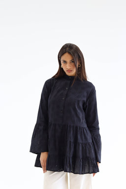 - A loose, long-sleeve tunic or blouse in black with a high mandarin collar and buttoned placket. It features a tiered, ruffled hem and eyelet or cutout detailing across the fabric, giving a light, airy look.
- Intended audience: women's.
- Notable attributes: dark black fabric, lightweight eyelet detailing, tiered layered hem, relaxed fit with slightly flared sleeves.