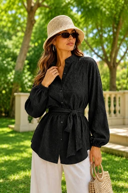 - What the product is: A black embroidered shirt with a waist tie belt, long puff sleeves, and a button-front design.
- Apparent audience: Women's (styled on a female model with a relaxed, chic look).
- Notable attributes: Matte black fabric with embroidery details, a shirt collar, full-length sleeves with elasticized cuffs, a self-tabric belt at the waist, and a slightly A-line hem. The styling includes a straw hat and light-colored pants, suggesting a casual to smart-casual, warm-weather vibe.