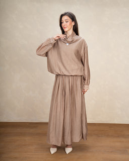 - Product: A long-sleeve, knee- to ankle-length blouse and skirt set in a soft, neutral taupe color. The outfit features a loose-fitting, high-neck blouse with balloon sleeves tucked into a full, flowing skirt with subtle pleats.

- Audience and styling cues: Appears designed for women, with a modest, elegant, and feminine styling suitable for dressy or office wear.

- Notable attributes: Lightweight, textured fabric in a taupe/beige shade; minimal jewelry visible; simple pointed-toe shoes in a light color. The look emphasizes a coordinated, comfortable, and vintage-inspired silhouette.