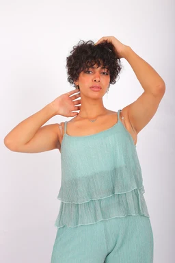 - A light teal, sleeveless layered top or crop top with thin spaghetti straps, worn by a female model. The top features multiple sheer, ruffled tiers over a matching underlayer, creating a soft, airy silhouette.
- Audience: women's sizing, judged from the model and styling.
- Notable attributes: pale mint/seafoam colour, sheer lightweight fabric with layered, tiered ruffles; casual, flowy, layered camisole/top style.