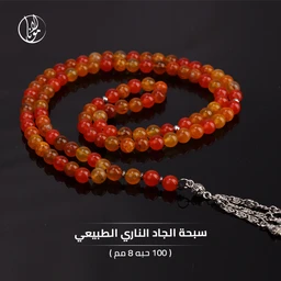 هذا منتج سبحة وجاهة بالجاد الطبيعي الملون، مكوّنة من 100 حبة بحجم 8 مم ومرصعة بتدرجات اللون البرتقالي-الأحمر. الجمهور المستهدف يبدو من النساء والرجال معًا (unisex)، بناءً على التصميم واللون المودرن. المواد الظاهرة هي حجر جاد طبيعي شفاف بلون عقدة متدرج من الأحمر إلى البرتقالي، وبجانبها سلسلة فاصل فضية اللون. الأسلوب عصري وبسيط مع خيط سميك وشرابة فضية في نهايته.