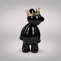 This is a glossy black bear figurine wearing a gold crown, styled in a playful, collectible toy form. The intended audience appears unisex adults or teens collecting decorative figures. Notable attributes include the smooth, shiny black ceramic/porcelain surface, a metallic gold crown, and a simple, rounded bear silhouette with minimal facial detail. The name on the chest side suggests branding but no brand is visible.