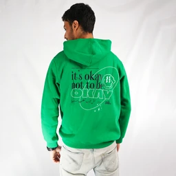 - A bright green unisex hoodie shown from the back, with a large hood and long sleeves.
- The visible text graphic on the back reads “it’s okay not to be OKAY” in a bold, layered design, with additional circular and line elements around the text. The hoodie appears to be made of a standard soft fleece material, and it is paired with light gray jeans in the photo.
- Intended audience: unisex (fits both men and women judging by styling). Notable attributes: vivid green color, graphic print on back, hooded sweatshirt, long-sleeve, midweight fleece, casual streetwear style.