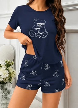 - What the product is: A navy pajama set featuring a teddy bear print, consisting of a short-sleeve T-shirt and matching shorts.
- Apparent audience: Women's, inferred from the fit, cut, and styling shown on a female model.
- Notable attributes: Navy blue fabric with light blue outlined teddy bear prints; relaxed short-sleeve top with a side knot or cropped look and matching relaxed-fit shorts with an elastic waistband. Materials appear soft and lightweight, suitable for loungewear or sleepwear.