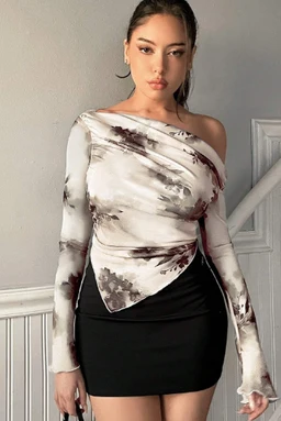 - Description: A women's long-sleeve top with an asymmetric, draped hem that ties at the side, shown worn off one shoulder.
- Intended audience: Women (unisex styling not indicated; model appears female).
- Notable attributes: Tie-dye print in neutral marbled whites and browns, lightweight stretch fabric, off-shoulder neckline with a wrap-front asymmetrical hem over a black mini skirt. Style: casual-urban with a statement wrap and asymmetrical silhouette.