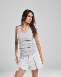 This is a sleeveless, scoop-neck tank top shown on a female model, styled casually in light heather gray. The outfit appears designed for a unisex or women's audience, with a simple, stretchy knit fabric and a classic ribbed finish. Notable details include the soft, neutral gray color and a reversible or versatile fit that pairs with light denim shorts as pictured.