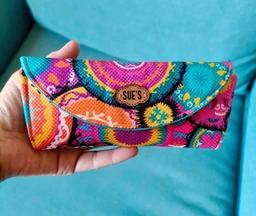 A colorful, curved glasses case with a bright, patterned fabric exterior and a turquoise interior. It appears designed for unisex use, suitable for holding two pairs of glasses, as shown by two pairs of eyeglasses inside. Notable attributes include a vibrant multicolor print, fabric construction, a magnetic snap closure, and a soft padded lining for lightweight protection.