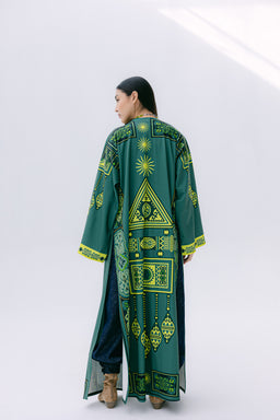 - The product is a long, flowing kimono-style outer garment with a geometric, bright green and yellow print on a dark teal base. It features wide sleeves and an open front, draping to mid-calf length on a model.
- Intended audience appears to be unisex or women’s, based on the styling and fit on the model.
- Notable visible materials and details: bold tribal/geometric print, long proportions with wide sleeves, yellow trim accents at the cuffs and hem, and a relaxed, robe-like silhouette. The model wears it over dark pants and ankle boots.