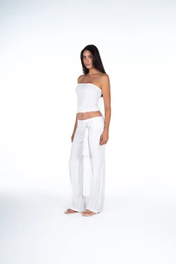 - Product: O-Ring White Set appears as a white, two-piece outfit consisting of a strapless bandeau top and wide-leg pants with a matching sash or belt detail.
- Audience and styling: Designed for women, shown on a female model with a casual, summery vibe. The look is light, airy, and minimalist.
- Materials, color, style: Bright white fabric with a soft, textured or slightly patterned surface; strapless crop top and flowing wide-leg pants with a tied waist, giving a relaxed, resort or lounge style.