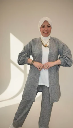 - What the product is: A winter/open cardigan set with a belt, shown as a coordinated two-piece outfit (cardigan over a top with matching pants).
- Apparent intended audience: Unisex leaning toward women; styling, jewelry, and hijab suggest women's fashion.
- Notable visible attributes: Soft grey knitted fabric, open-front cardigan with a belt, matching grey pants, white inner top, white hijab, statement gold-toned necklace. The look is cozy, modest, and tailored with a relaxed fit.