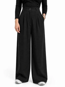 - What the product is: A pair of wide-leg, buttoned flowy pants in black.
- Apparent audience: Women's (model wearing a fitted long-sleeve top and tailored high-waist pants suggests feminine styling).
- Notable attributes: High-waisted with a front button closure and a drawstring/elastic-like tie at the waist, wide full-length legs, smooth matte fabric, and side pockets. The look is loose, drapey, and tailored with a clean, minimal style.