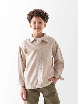 - What the product is: A beige gabardine jacket worn by a young boy, styled with a casual, oversized fit and button-front closure.
- Apparent audience: Boys (youth) based on the size and model.
- Notable attributes: Light tan/khaki gabardine fabric, long sleeves with cuffs rolled, a single chest pocket, collared neckline, and a relaxed button-down styling. The color appears neutral and earthy, with a simple, minimal design.