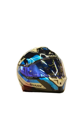 - What the product is: A full-face motorcycle helmet with a futuristic, angular visor design.  
- Apparent audience: Unisex or riders (fits both men and women based on styling; no gendered features).  
- Notable attributes: Gold and black outer shell with blue mirrored visor, sharp geometric graphics, ventilation vents at the chin and top, and a prominent SHARK logo on the side. Material appears to be a hard composite shell with a tinted/reflective visor.