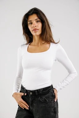 A white, long-sleeve top with a square neckline. The model appears to be female, wearing a fitted silhouette that highlights the torso. The fabric looks smooth and stretchy, likely a jersey or knit in solid white; styling is simple and casual, paired with dark jeans.