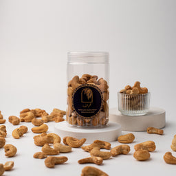 - Product: Vietnamese cashews in a clear cylindrical jar with a dark label, surrounded by loose nuts on a white display.
- Intended audience: unisex (suitable for both men and women) judging from the neutral packaging and presentation.
- Notable attributes: light-to-medium roasted cashews with a golden-brown color in a transparent jar; black round label on the jar; simple, minimalist white and gray display with pedestal platforms.