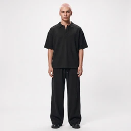 - Product: A man’s black polo-style top with oversized short sleeves and a relaxed fit, paired with wide-leg black pants. The overall look is minimalist and monochrome.
- Audience: Menswear (unisex-leaning but the model is male, so described for men’s).
- Materials/attributes visible: Solid black fabric, polo collar with a short placket, loose short-sleeve top, and very wide, drapey trousers. Simple, clean lines with a casual, modern silhouette. No brand logos visible.