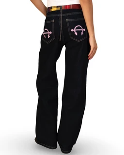 This is a pair of dark-indigo/black denim jeans designed for girls, shown from the back with a loose, wide-leg cut. The jeans feature pink stitched back pockets with decorative emblem details and a multicolor plaid waistband peeking above the top edge. The overall styling is casual denim with a playful, colorful accent.