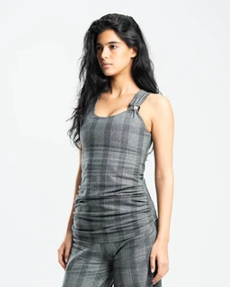 - Product: A sleeveless, ruched fit top and matching pants set in a grey Prince of Wales check. The fabric appears lightweight with a subtle plaid pattern in varying grey tones.
- Audience and style cues: Designed for women; features a fitted tank-style top with wide straps and a high-cut leg silhouette on the pants, giving a modern, cohesive loungewear or casual-smart look.
- Notable materials and attributes: Grey check suiting plaid pattern, soft stretch fabric, visible ruched gathering at the sides of the top and pants, and metal buckle details on the strap fasteners.