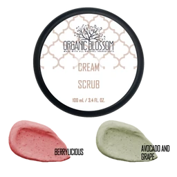 This is a cosmetic cream scrub product, shown in a round white container with a black rim. The label indicates a natural/organic theme, with the scent variants displayed as color swatches: pink “Berrylicious” and pale green “Avocado and Grape.” The visible attributes highlight an organic product aesthetic, creamy scrub texture, and fruit/avocado-based flavor notes, with a 100 mL (3.4 fl oz) size. Audience appears unisex, based on neutral packaging and styling.