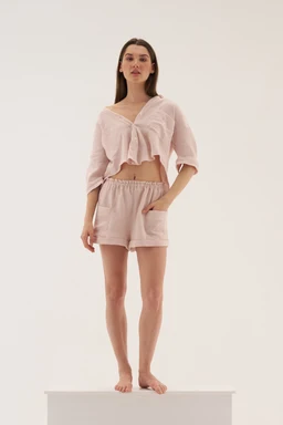 - Product: A matching lounge set consisting of a cropped top with short sleeves and coordinating shorts.
- Audience: Women's or unisex depending on styling; shown on a female model, suggesting women's sizing.
- Notable attributes: Light pink, fluffy/soft textured fabric with a relaxed fit. The top features a front tie detail and a V-neck with a cropped length; the bottoms are high-rise/elastic waist shorts with side pockets. Overall look is casual, cozy loungewear.