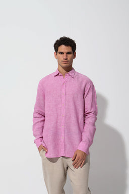 This is a pink premium linen shirt worn by a male model, styled for a casual to smart-casual look. The shirt features a relaxed, slightly oversized fit with a button-down collar and long sleeves, paired with light beige trousers for a soft, airy appearance. Visible attributes include the pink linen fabric, natural drape, and a clean, minimal design without visible branding.