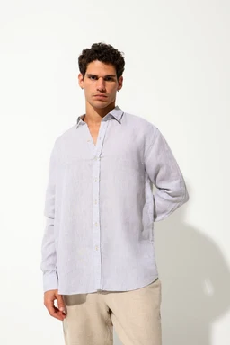 - What it is: A light grey premium linen shirt worn by a male model. The shirt features a relaxed fit with a standard collar and button front, long sleeves with cuffs, and a slightly curved hem.
- Intended audience: Men (adult).
- Notable attributes: Light grey linen fabric with a natural, breathable texture; concealed placket with visible buttons; relaxed, casual styling suitable for smart-casual looks. The model pairs it with beige trousers for a neutral, understated ensemble.
