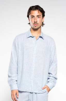 This is a light Arctic blue linen shirt with a relaxed, oversized fit. The model appears to be a men's presentation, suggesting a unisex to menswear audience; the shirt features a classic collar, button-front placket, long sleeves, and a breathable linen fabric with a subtle heathered texture. Notable attributes: pale blue-blue color, loose silhouette, and lightweight, textured linen material.