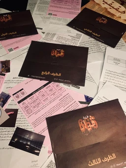 - What the product is: A set of Arabic language printed materials, including dark-colored booklets or cards laid out on a surface, with some pink and white sheets visible beneath. The design suggests a literary or educational package rather than a single book.
- Apparent audience: Unisex; the styling and neutral dark tones, along with the Arabic text, do not indicate a specific gender, and the materials appear suitable for general readers.
- Notable attributes: The visible items are dark brown/black with copper/orange Arabic script or logo, arranged among lighter pink and white sheets. The layout shows multiple cards/booklets with minimalistic, bold typography and a formal, premium presentation. Material impression is matte card stock or thin booklet pages.
