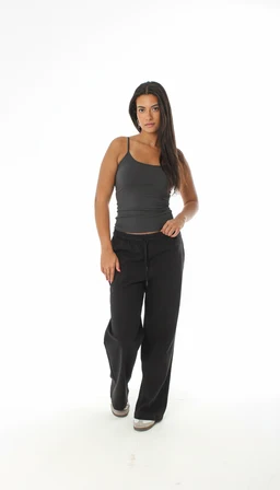 - Description: A sleeveless, fitted spaghetti-strap tank top in a dark charcoal/black color, shown on a female model. The top has a snug, cropped silhouette with narrow shoulder straps, paired with loose-fitting black pants.
- Audience and styling cues: Appears targeted to women, with a simple, casual everyday look suitable for a relaxed or lounge ensemble.
- Notable attributes: Slim spaghetti straps, square-ish scoop neckline, solid dark fabric with a soft, stretchy appearance; overall minimalistic, contemporary style.
