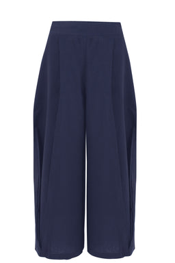 These are navy blue wide-leg pants made from linen, featuring a relaxed, flowy silhouette. The model suggests a unisex or women’s styling with a high, elastic or smooth waistband and long, voluminous legs that taper slightly at the hem. Visible attributes include the lightweight linen texture, solid navy color, and a comfortable, loose-fit drape.