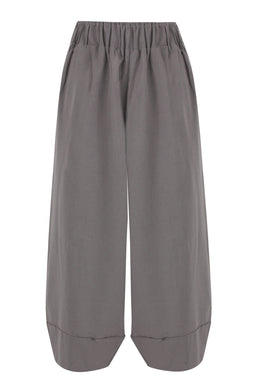 - What it is: A pair of light-to-mid grey balloon-leg pants with an elastic waistband and wide, voluminous legs that taper into a cuffed hem at the bottom.
- Intended audience: Appears unisex or could be styled for women; model styling is not shown, so inferred as general wearable pants.
- Notable attributes: Made from a linen-like fabric with a soft, matte finish; grey color; high-volume balloon silhouette; elasticized waistband; wide-leg cut ending in cropped, cuffed hems.
