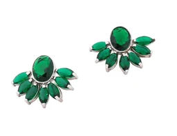 These are a pair of decorative clip-on earrings featuring emerald green teardrop and marquise-shaped stones arranged in a sunburst/flower motif with a central oval stone. The design suggests a formal, feminine style suitable for women, with a silver-tone metal setting and vibrant green gemstone-like accents. Visible attributes include bright green stones, a clustered petal layout, and a polished metal backing with clip-on findings.