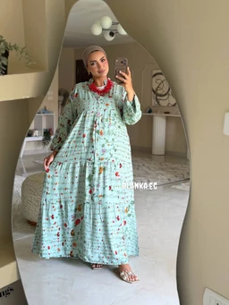 - A full-length, mint green maxi dress with a loose, flowing silhouette and long puff sleeves. It features a soft, all-over pattern and a ruffled tier at the lower skirt, giving an elegant, modest look.
- Appears targeted to women; styling includes a hijab (headscarf) and red necklace, with open-toe flat sandals. The material looks lightweight and breathable, suitable for warm weather, with a gathered waistline and tiered skirt for added volume.