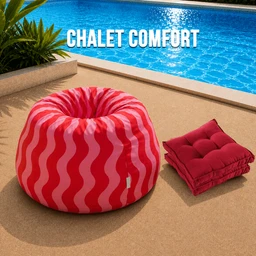 This is a large, round bean bag chair in a bright pink and white wavy pattern, placed poolside on a tan surface. It appears aimed at a general/unisex audience for lounging, with a soft, cushy fabric look. Notable attributes include the bold pink-and-white striped fabric, and the matching folded red cushions/pillows stacked beside it, suggesting a comfy outdoor relaxation setup.