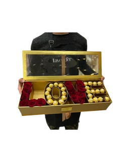 - What the product is: A gold-toned gift box arranged to spell out the word “LOVE” using red velvet roses for the letters and gold-wrapped chocolates lining the others, with a clear lid and small label on the front.
- Apparent audience: Unisex (appears suitable for any recipient); the styling is romantic and gift-like, often used for couples or special occasions.
- Notable attributes: Gold metal box with a transparent lid, red rose-textured letters formed from artificial roses, and gold-wrapped candies arranged to spell or complement the word; overall elegant, luxurious, and celebratory in style.