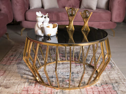 - What the product is: A round coffee table with a gold-tone geometric metal base and a glossy dark top.
- Apparent audience: Unisex, suitable for living rooms; styling reads as modern-luxe with a glamorous, contemporary feel.
- Notable attributes: Gold metal frame with angular, faceted geometric legs; black (or very dark) tabletop; decorative items on top (white ceramic sculptures and gold-toned accessories) contributing to a luxurious aesthetic. Material emphasis on metal frame and glass-like top finish.