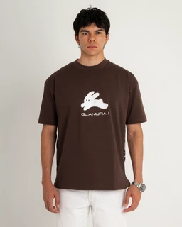 A unisex short-sleeve T-shirt in a deep brown color featuring a white graphic of a rabbit in the chest area. The shirt is worn by a male model, suggesting a men's sizing and styling. Notable details include the lightweight cotton-look fabric and the white rabbit graphic with text underneath, giving a casual, streetwear vibe.