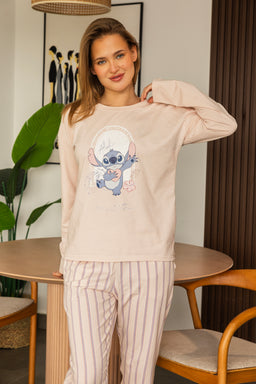 - What the product is: A pale pink/soft beige pajama set featuring a Stitch character graphic on the top and vertical striped pants. The top is a long-sleeve crewneck sweatshirt; the bottoms are loose-fitting pajama pants with light pink and white stripes.
- Apparent audience: Women (adult model styling and fit suggest women's loungewear).
- Notable attributes: Comfortable knit fabric in a pastel tone; graphic of Stitch on the top; coordinating striped bottoms; relaxed, cozy loungewear set suitable for bedtime or lounging at home.