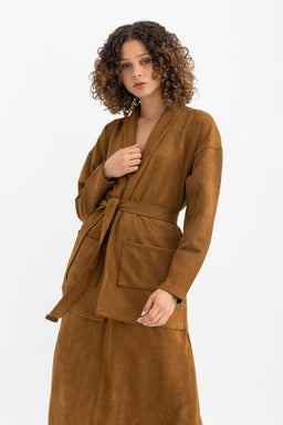 - A brown mohair ensemble featuring a belted wrap-style cardigan or robe with a matching skirt. The model wears a loose-fitting, V-neck top with a waist tie and long sleeves, and a knee-length skirt in a soft, fuzzy brown mohair-like fabric.
- Intended audience: women (judging from the model styling and silhouette).
- Notable attributes: warm caramel/brown color, plush mohair-like texture, matching two-piece set with a belt and patch pockets on the cardigan, and a relaxed, chic, minimalist style.
