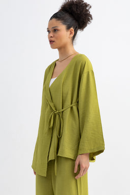 This is a women’s lounge set consisting of a roomy, open-front cardigan-style top with a matching belt over a white inner layer. Intended for a female audience, the styling is relaxed and drapey with wide, batwing sleeves. Notable materials and colors include a soft, olive/apple green knit fabric and a tied waist belt that emphasizes a casual, wrap-like look. The overall set has a soft, casual, knitwear aesthetic.