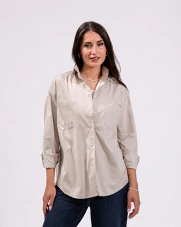 A beige poplin shirt with a relaxed, oversized fit worn by a female model. Intended audience appears to be women; the light, neutral shade and casual styling with rolled sleeves suggest a versatile, everyday shirt. Notable details include a classic button-front design, a pointed collar, front pockets, and a crisp poplin fabric with a soft sheen.