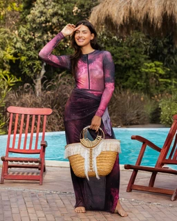 - What the product is: A long-sleeve, full-length swimsuit with a velvet finish in a galaxy print, featuring a front zipper and fitted silhouette.
- Apparent audience: Women (adult), based on the model and styling.
- Notable attributes: Velvet-like fabric with a galaxy-inspired purple-pink color palette, long sleeves, full coverage, zip front, and a floor-length cut.