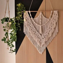- What the product is: A wall hanging macrame decor piece made of natural rope/materials arranged in layered chevron/diamond patterns with long fringe, designed to be mounted on a wall.
- Apparent audience: Unisex (suitable for home decor; displayed in a neutral setting).
- Notable attributes: Natural beige/cream color, handmade macrame knotting, large triangular/chevron shape with multiple fringe tiers, dimensions roughly 100x110 cm as per title, designed to hang from a rod or rope.