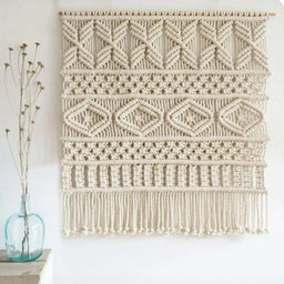 - What it is: A large wall hanging made from natural cotton cord with a wooden dowel at the top (macrame wall art). It features a series of textured knots and geometric patterns, finished with a long fringe at the bottom. Size appears around 80x80 cm as labeled.
- Audience: Unisex — suitable for living rooms or bedrooms in both men's and women's spaces.
- Notable attributes: Natural cotton fibers in an off-white/cream color, multiple decorative macrame knot styles arranged in horizontal bands, intricate geometric motifs, rustic boho style, with a fringe fringe at the bottom.