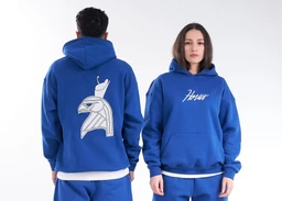 - What the product is: A royal blue hoodie featuring a large graphic on the back and a front logo text. The hoodies are worn by a male (back view) and female (front view) model, positioned in a studio setting with a white background.
- Apparent audience and styling: Appears to be unisex or broadly gender-neutral, styled as casual streetwear with a relaxed fit, large front kangaroo pocket, and a white undershirt peeking at the hem.
- Notable attributes: Material looks like soft fleece/sweatshirt fabric; bold blue color; front script text on the chest and a large graphic illustration on the back; hooded with white drawstrings and ribbed cuffs/hem.