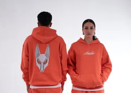 - What the product is: A bright orange/red hoodie with a large graphic on the back and a script logo on the front. It includes a drawstring hood and front kangaroo pocket.
- Apparent audience: Unisex or general adult sizing, judged from the model styling and fit.
- Notable attributes: Solid neon-orange color, white graphic on the back resembling an animal/mascot mask, and a white script logo on the front. Casual, streetwear style with a relaxed fit and ribbed cuffs/hem.