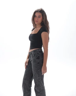 This is a cropped, short-sleeve black top with a square neckline, fitted through the bust and waist. The model appears to be female, styled with high-waisted, dark-wash jeans for a casual, modern look. Notable features: solid black fabric, cap or short sleeves, square neckline, and a slim, body-skimming silhouette.