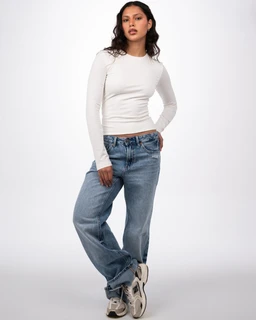 - A long-sleeve white knit top worn by a female model. 
- Intended audience: women (based on fit and styling). 
- Notable attributes: lightweight cotton-looking fabric, crew neck, fitted cropped silhouette with full-length sleeves; paired with relaxed medium-wash blue jeans and casual sneakers for a laid-back, everyday look.